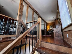 A wooden staircase with a black railing leading to a room with a wooden floor and a window.
