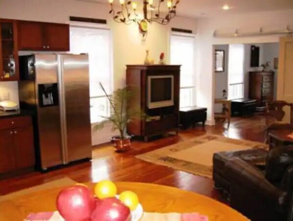 A spacious living area with a large wooden dining table, a sofa, and a television.