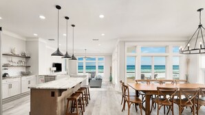Een ruime keuken met een groot eiland, houten stoelen en uitzicht op de oceaan.