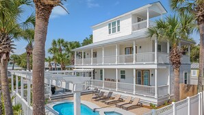A two-story building with a pool, white exterior, and balconies.