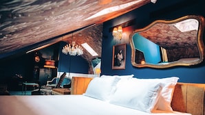 A bedroom with a large bed, a wooden ceiling, a chandelier, a mirror, and a clock on the wall. - Pensão Amor Madam’s Lodge (Lisbon)