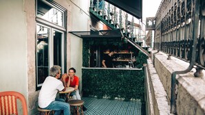 A narrow outdoor seating area with a bar, a patterned floor, and a staircase. - Pensão Amor Madam’s Lodge (Lisbon)
