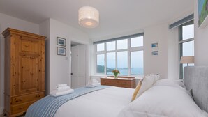 Une chambre à coucher avec un grand lit, une armoire en bois, une fenêtre donnant sur un beau paysage et une table de chevet avec une lampe.