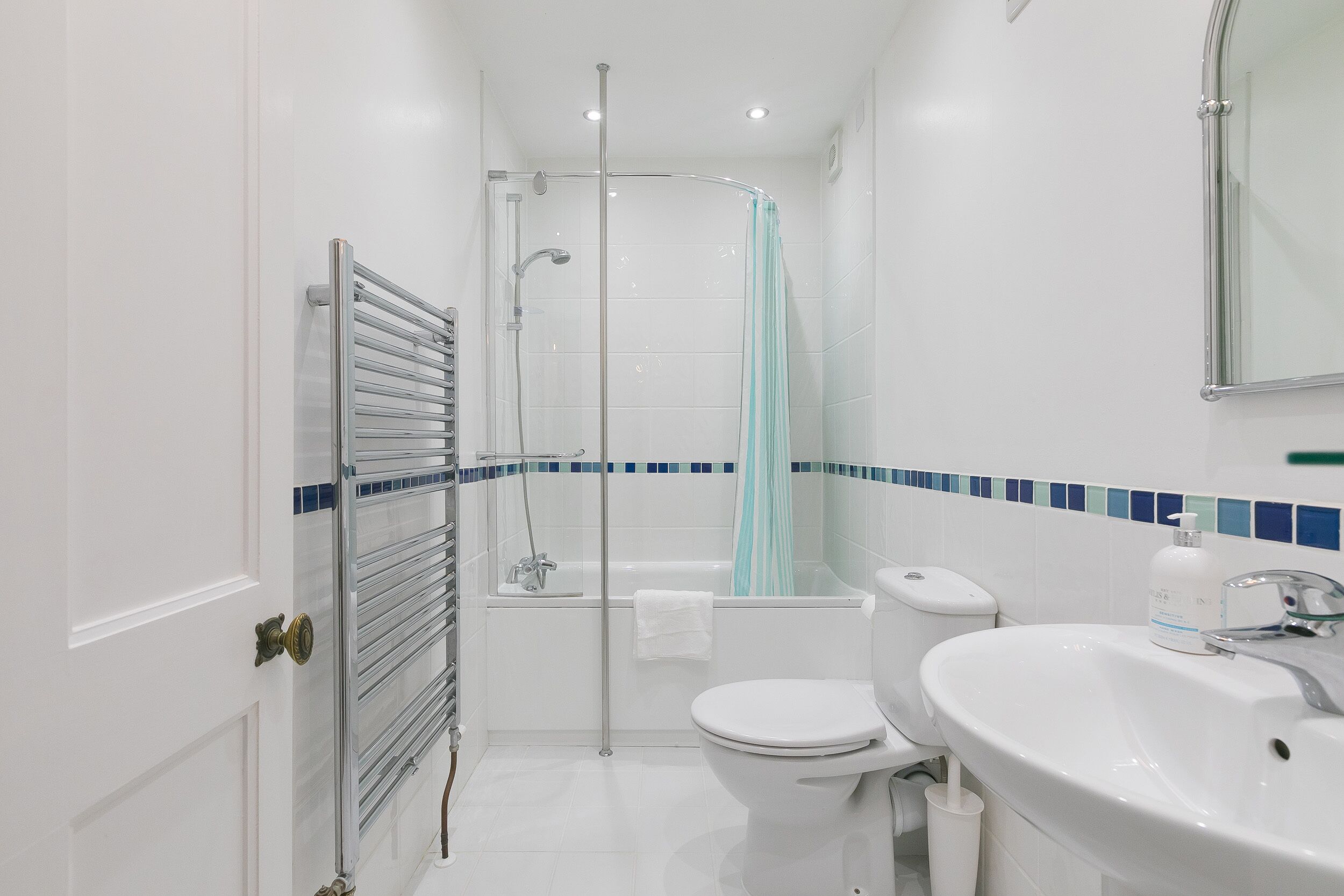 A modern bathroom with a glass shower enclosure, a white toilet, a bathtub, and a sink with a mirror above it.