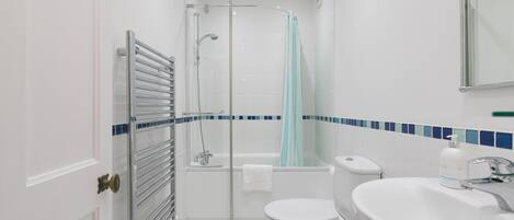 A modern bathroom with a glass shower enclosure, a white toilet, a bathtub, and a sink with a mirror above it.