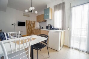 A compact living space with a dining area, kitchenette, and a sliding glass door leading to a balcony. - Urban Beach (1D) (Ρέθυμνο)