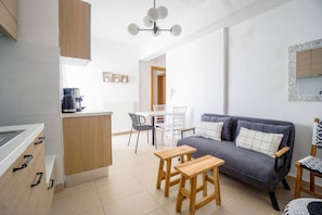 A modern kitchen with a dining area, a sofa, and a small table.