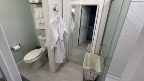 A bathroom with a toilet, a sink, a mirror, and a shower area. - Starfish Room — Coastal Luxury & Romantic Comfort at Mar Bella (Rehoboth Beach)