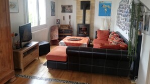 Een gezellige woonkamer met een open haard, een bank, een televisie en een boekenkast.