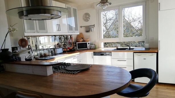 Een moderne keuken met witte kasten, een houten eiland en een raam dat voor natuurlijk licht zorgt.