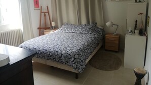 Een slaapkamer met een bed, nachtkastje, lamp, wereldbol en een kaart aan de muur.