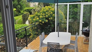 Een terras met een tafel, stoelen, een barbecue en uitzicht op groen.