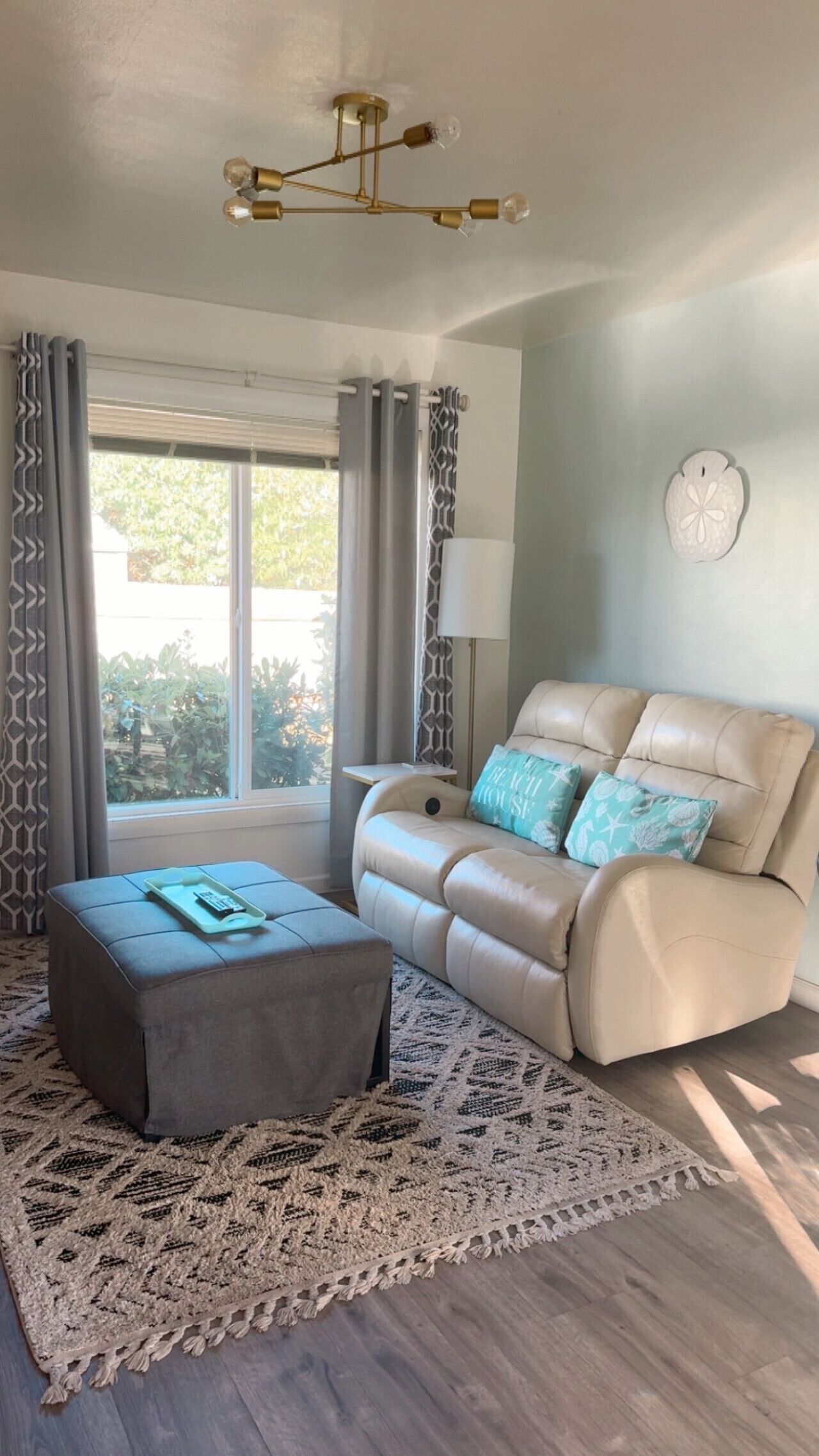 A living room with a beige sofa, a patterned rug, and a ceiling light fixture.