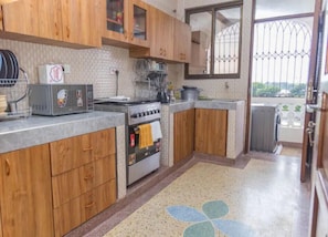A kitchen with wooden cabinets, a stove, a toaster, and a window with a view.