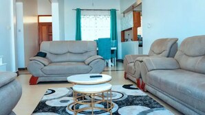 A living room with two sofas, a small round table, and a patterned rug. - Hibiscus Homes-Shanzu(3bedroom) (Mombasa)