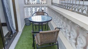 A small balcony with a round table and two wicker chairs, a metal railing, and a view of the street. - Divine apartments (Mombasa)
