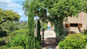 Un bâtiment rustique, doté d’une entrée en pierre, entouré d’une végétation luxuriante et d’arbres.