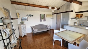 Une cuisine chaleureuse avec un plafond en bois, une table à manger avec des chaises, un canapé et un petit meuble.