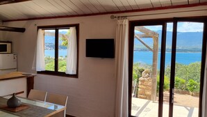 Une cuisine équipée d’un four à micro-ondes et d’un réfrigérateur, un coin repas avec une table et des chaises, et une grande fenêtre offrant une vue sur un lac et des montagnes.