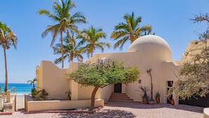 A building with a dome, palm trees, and a view of the sea.