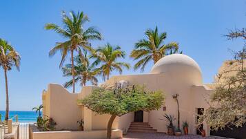 A building with a dome, palm trees, and a view of the sea.