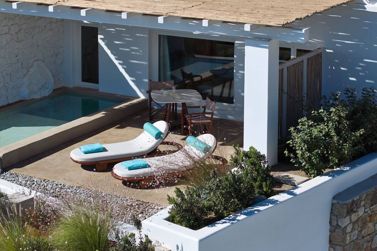 Un área de piscina exterior moderna con dos sillas de descanso y una mesa.