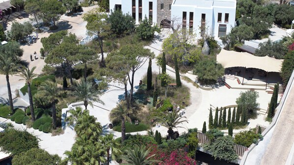 An aerial view of a resort with a pool, palm trees, and a white building with columns. - Nammos Hotel Mykonos (Mykonos)