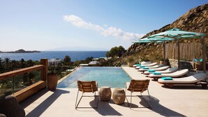 A poolside area with lounge chairs and umbrellas, overlooking a body of water. - Nammos Hotel Mykonos (Mykonos)