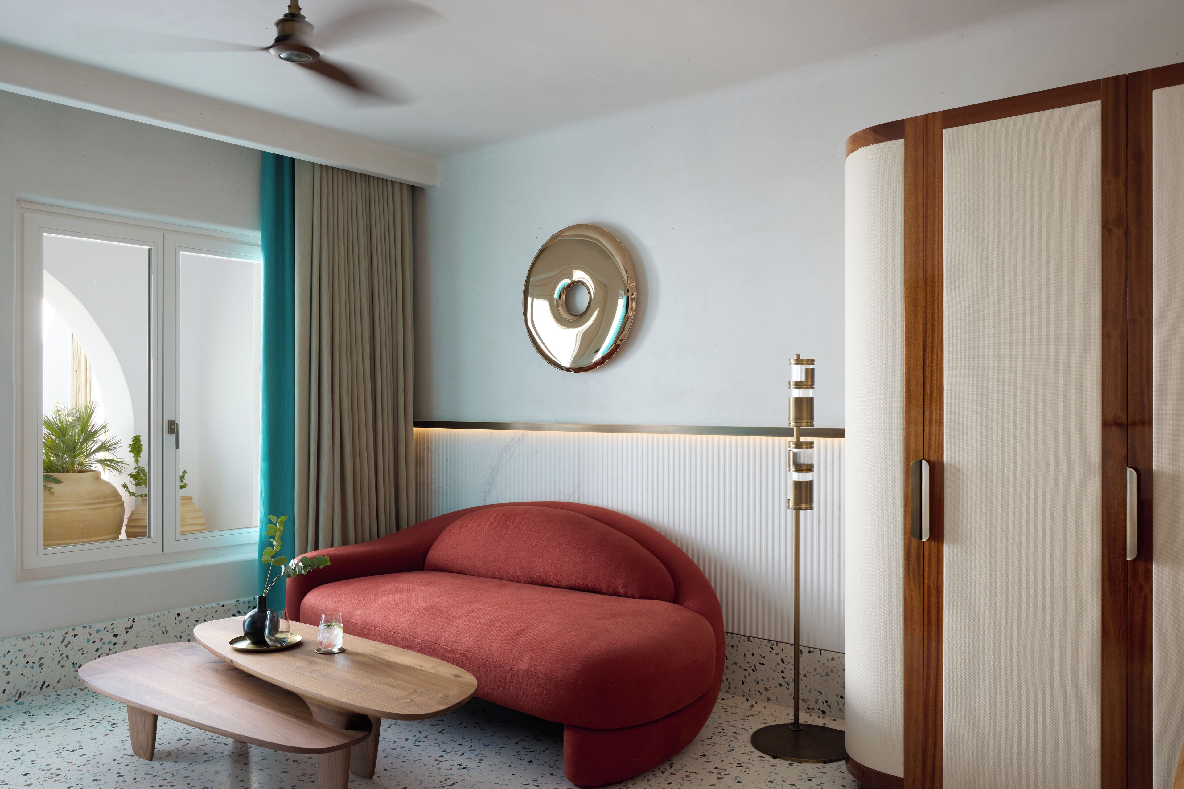 A modern room with a red sofa, a wooden coffee table, a floor lamp, and a large mirror on the wall.