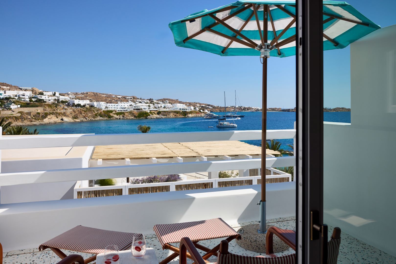 Un balcón con vistas al mar, edificios blancos y una terraza de madera.