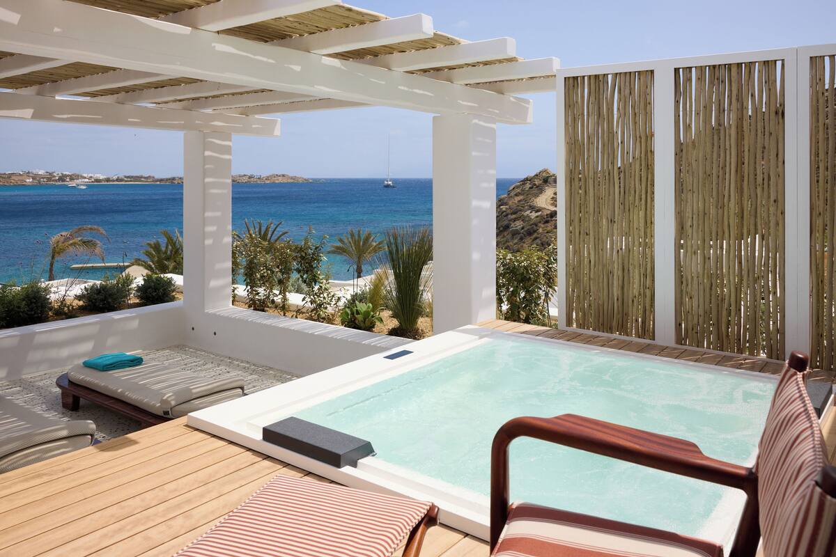 Una terraza en la azotea con jacuzzi, sillones de descanso y vistas al mar.