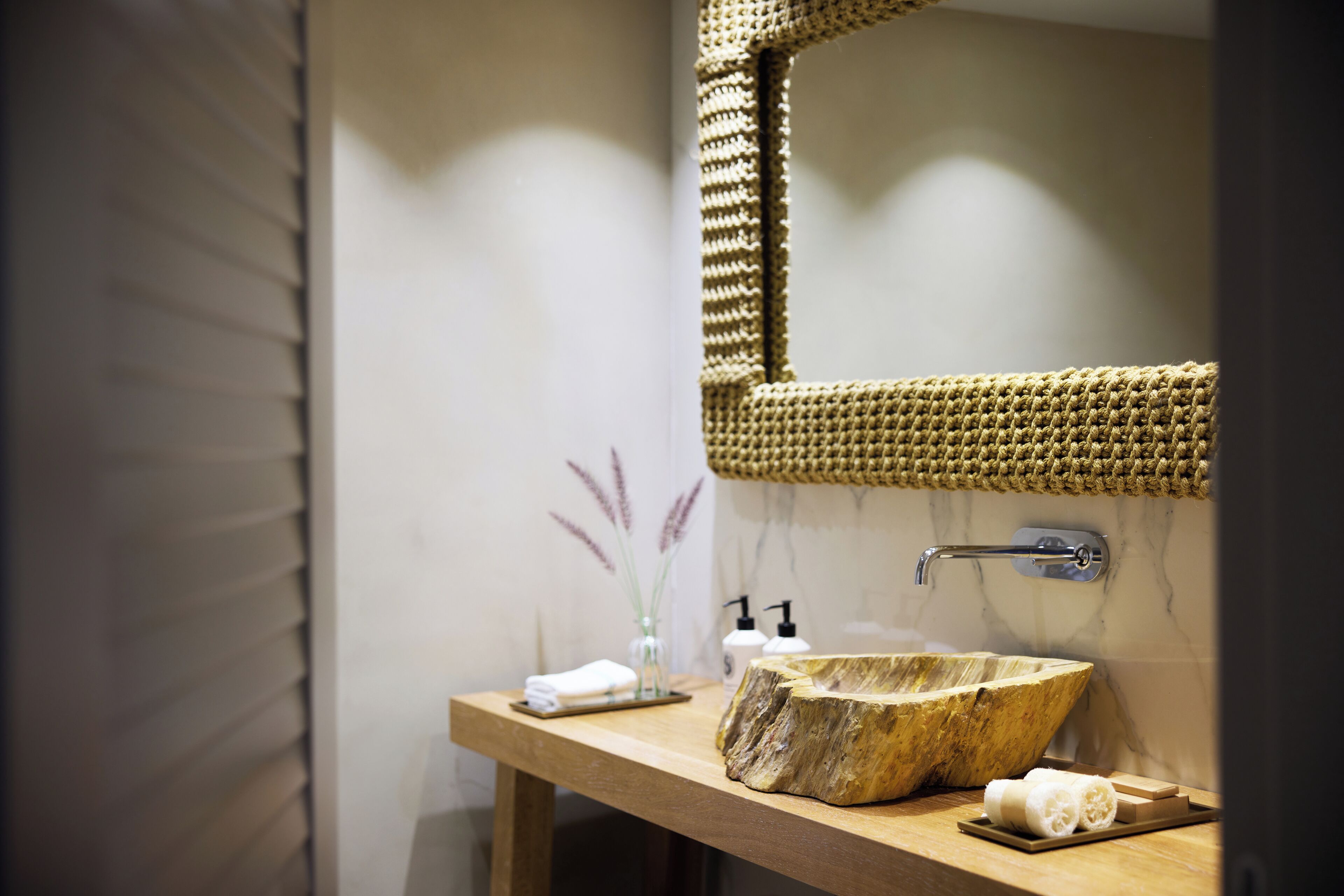 A bathroom with a wooden vanity, a large mirror, and a stone sink.