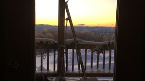 Una habitación con vista a un paisaje nevado y un atardecer.