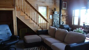 Una sala de estar acogedora con una escalera de madera, un sofá, una silla y una alfombra.