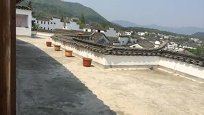 A rooftop with traditional tiled roofs and terracotta pots. - Huiyun Inn (Jing County)