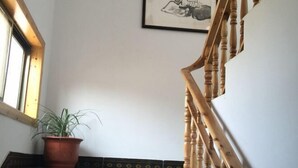 A staircase with wooden balusters, a potted plant on the landing, and a framed picture on the wall. - Huiyun Inn (Jing County)