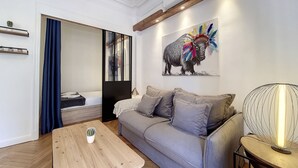 En moderne stue med en grå sofa, et træbord og et billede af et farverigt dyr på væggen.