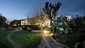 A house with a paved driveway leading to a front door, surrounded by cacti and shrubs. - Tenuta La Moresca – Villa with pool, and garden among the olive trees in Noto (Noto)