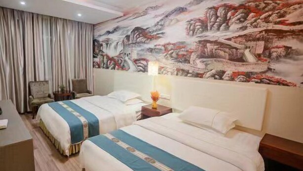 Habitación de hotel con dos camas, un mural grande en la pared, un escritorio y una silla.