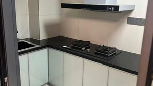Una cocina compacta con encimera negra, estufa integrada y campana extractora blanca.