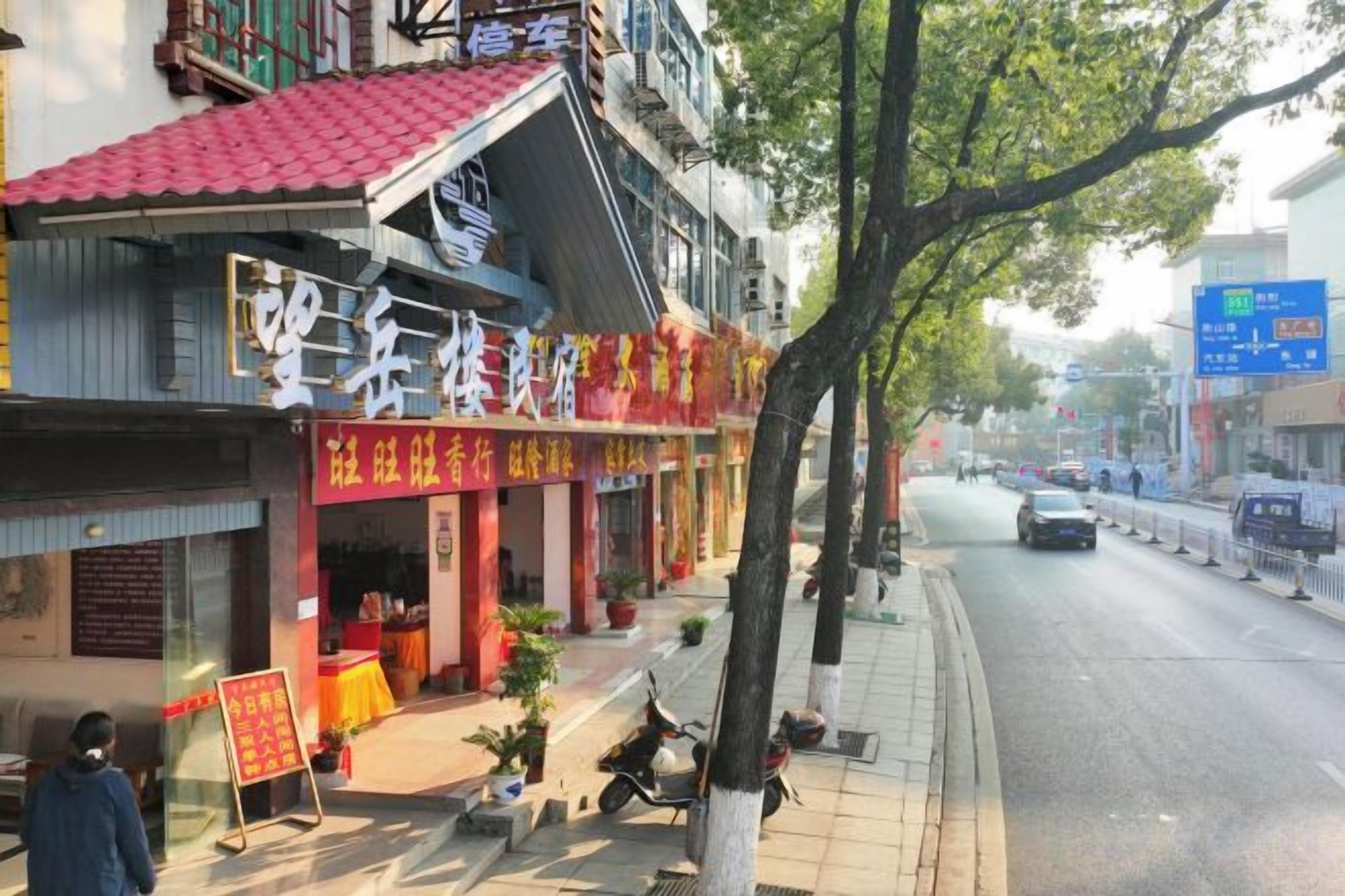 A street view with a building featuring a red roof and signage in a foreign language.