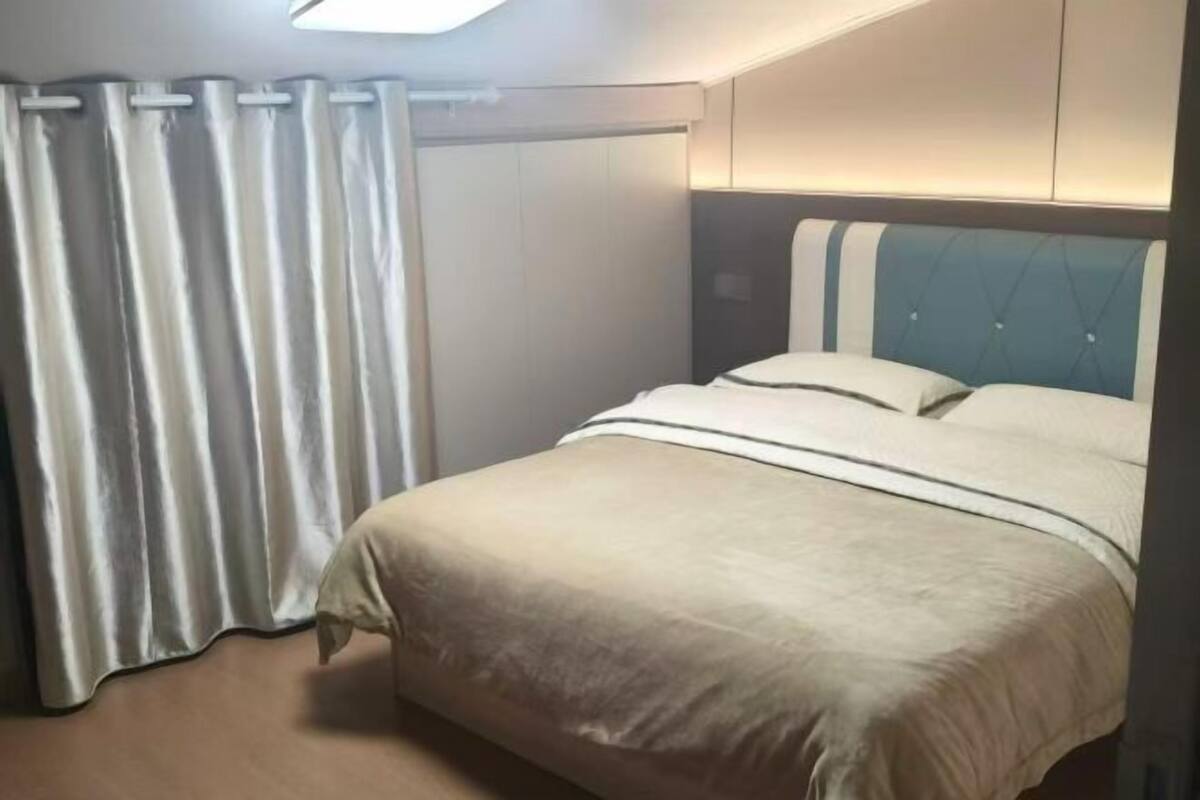 Un dormitorio con cama, cortinas y cabecero.