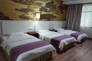 Quarto de hotel com três camas, um grande mural na parede e piso de madeira.