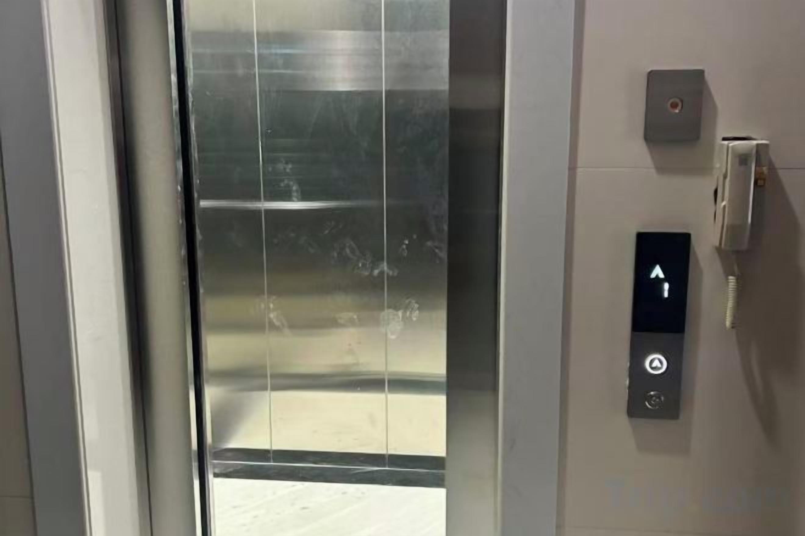 Un ascensor con un panel de control que incluye una flecha hacia arriba y un botón de encendido.