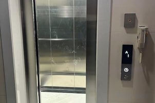 Un ascensor con un panel de control que incluye una flecha hacia arriba y un botón de encendido.