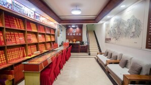 Un vestíbulo de hotel con una recepción, una escalera y una pared decorada con una pintura tradicional.