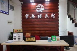 A reception desk with a wooden backdrop, a cash register, a digital screen, and a QR code for check-in. - Hengyang Wangyuelou Homestay (Mount Heng Scenic Area Nanyue Grand Temple) (Hengyang)