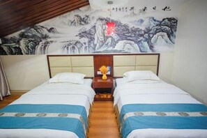 Una habitación con dos camas, un cabecero de madera, un mural en la pared y una mesita con un jarrón.