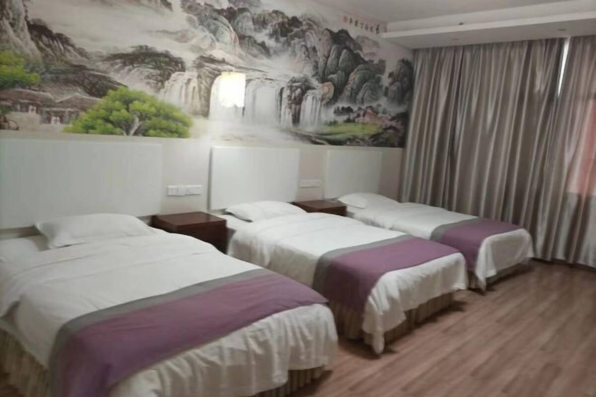 Habitación de hotel con tres camas, un mural de una cascada y una cortina.