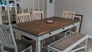 Ein Esszimmer mit einem Holztisch, weißen Stühlen und einer Bank.